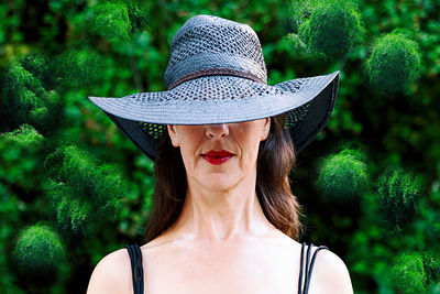 Portrait of woman wearing hat against trees