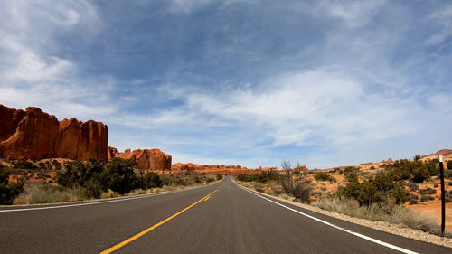 Road leading towards rock formation against sky