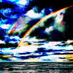 Low angle view of rainbow over sea against dramatic sky