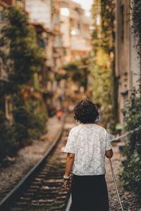 Rear view of woman walking on railroad tracks