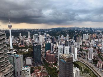 High angle view of city buildings against cloudy sky