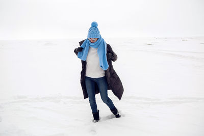 Girl running in a snowy field in a jacket and sunglasses