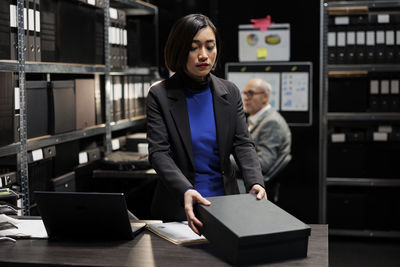 Portrait of young woman using mobile phone in office