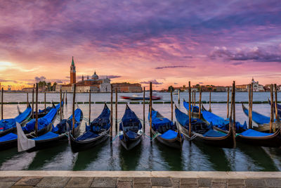 View of boats moored in city at sunset