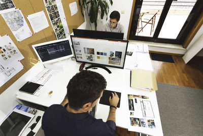 Rear view of man looking at camera while sitting on table