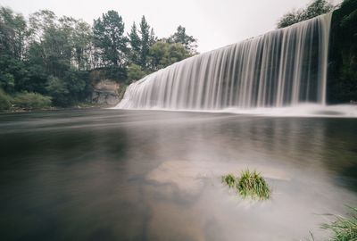 Scenic view of waterfall against trees