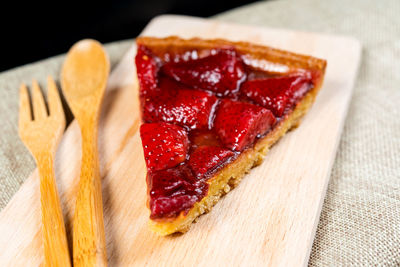 Close-up of strawberry tart with spoon and fork on table