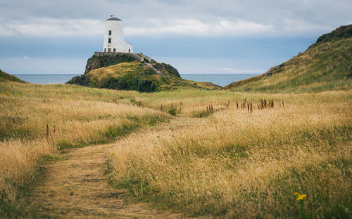 Lighthouse on field against sky