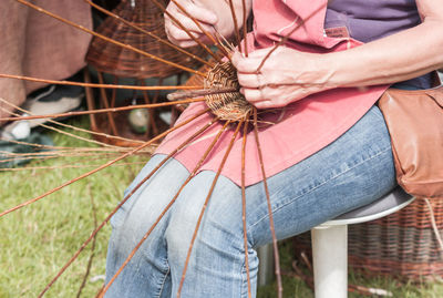 Midsection of woman making wicker basket