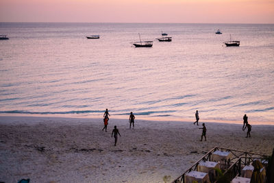 High angle view of people playing at beach against sky during sunset