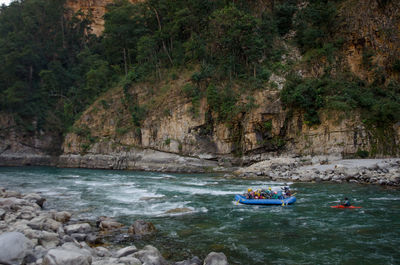 People on riverbank against trees