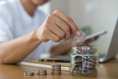 Close-up of hand holding glass of coins on table