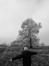 Rear view of man standing on field against clear sky