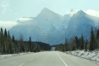 Road by snowcapped mountains against sky