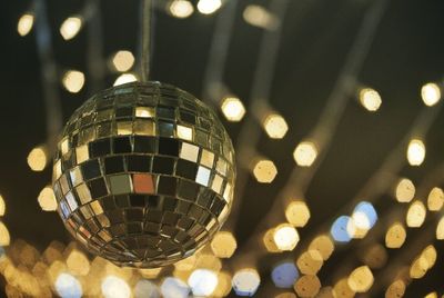 Low angle view of illuminated disco ball hanging in nightclub at night