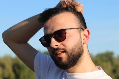 Close-up of young man wearing sunglasses against clear sky