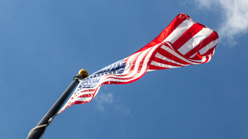 Low angle view of red flag against blue sky