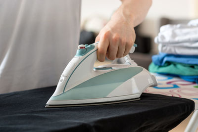 Midsection of man ironing garment on board