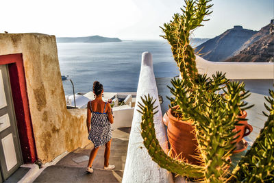 Rear view of woman standing by sea against mountains