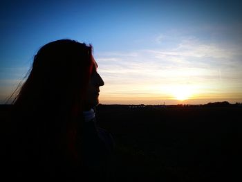 Silhouette person on field against sky during sunset