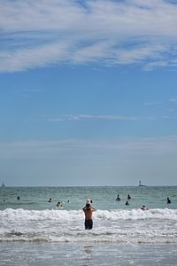 Rear view of woman standing in sea against sky