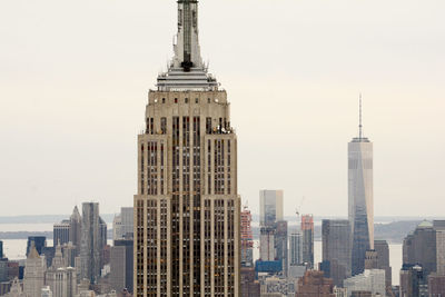 Empire state building against modern buildings at manhattan