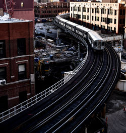 High angle view of train on railway bridge amidst buildings in city