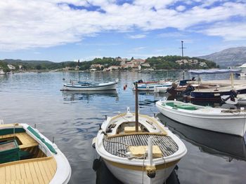 Boats moored at harbor against sky