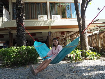 Portrait of woman sitting on hammock against plants