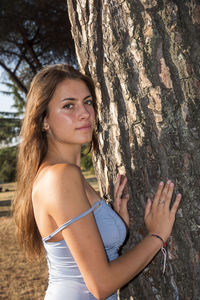 Portrait of young woman with tree trunk