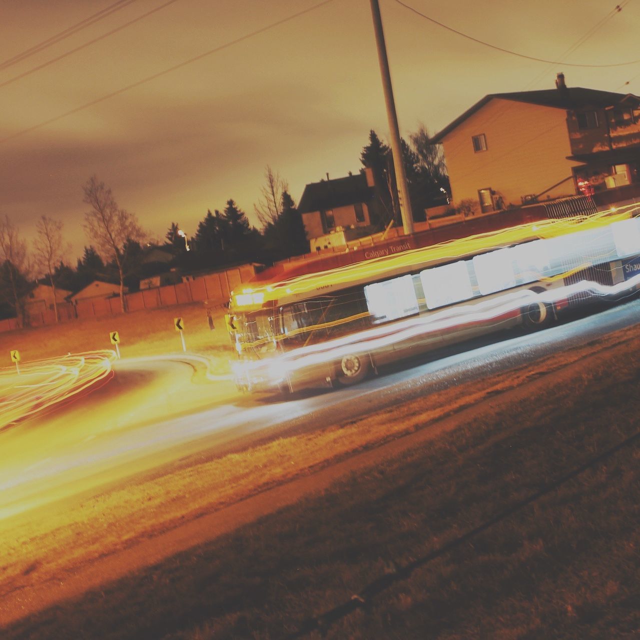 transportation, building exterior, architecture, built structure, sunset, mode of transport, land vehicle, illuminated, street, car, road, city, sky, railroad track, motion, long exposure, outdoors, public transportation, street light, on the move