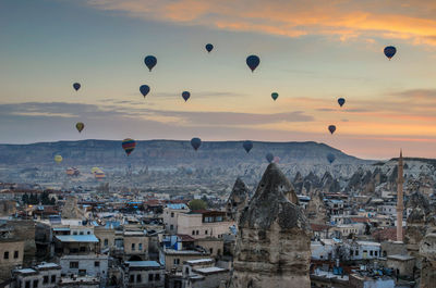 Hot air balloons over town against sky during sunset