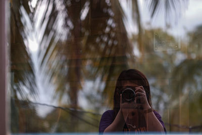 Portrait of woman reflection photographing camera