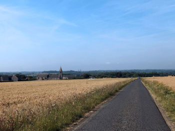 Road amidst agricultural field against sky