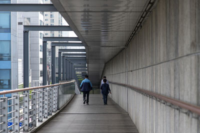 Rear view of people walking on footbridge