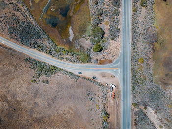 Top down aerial view of a t shaped road with some cars moving down the highway.