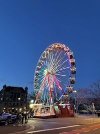 Ferris wheel in city against clear blue sky