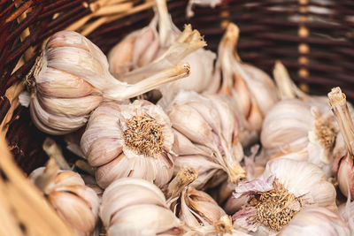 Many garlic bulbs and cloves in a wicker basket under the sun in a regional street food market