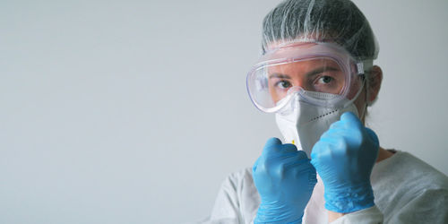 Low angle view of woman wearing surgical mask against white background