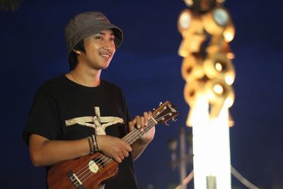 Low angle view of man playing guitar against sky at night