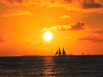 Silhouette sailboat in sea against sky during sunset