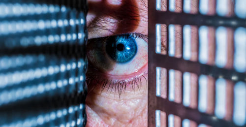 Close-up portrait of man seen through metal grate