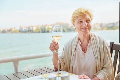 Elderly woman traveler sitting alone on the terrace of coffee shop