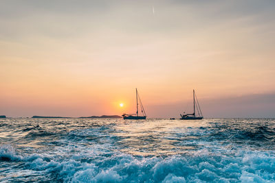 Sailboat sailing on sea against sky during sunset