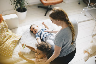 Mother with happy sons by sofa at home