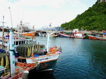 Boats moored at harbor against sky