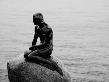 Man sitting on rock by sea