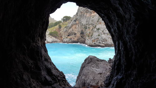 Scenic view of river in rocky mountains shot through cave