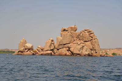 Rocks in sea against clear sky