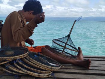 Man sitting in sea against sky